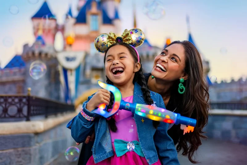 A mother and daughter holding a Key to Disneyland in front of Sleeping Beauty Castle