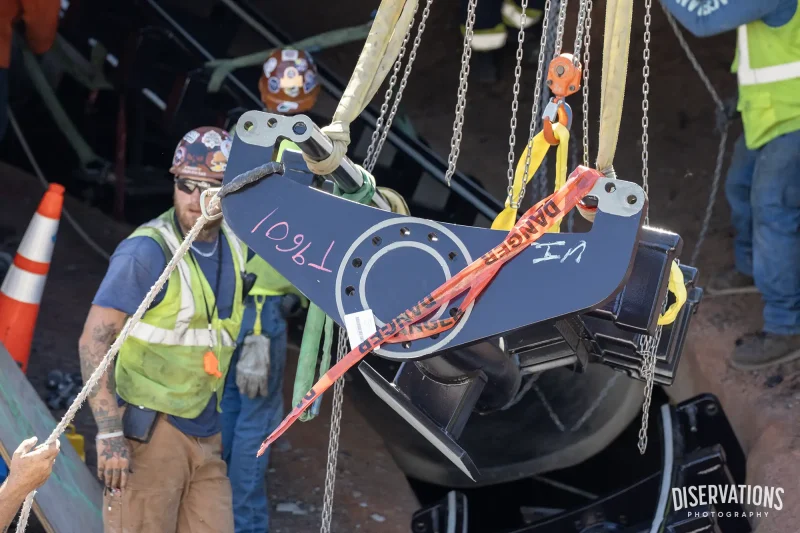 Crews using hoists to maneuver a piece of Big Thunder Mountain Railroad track into place
